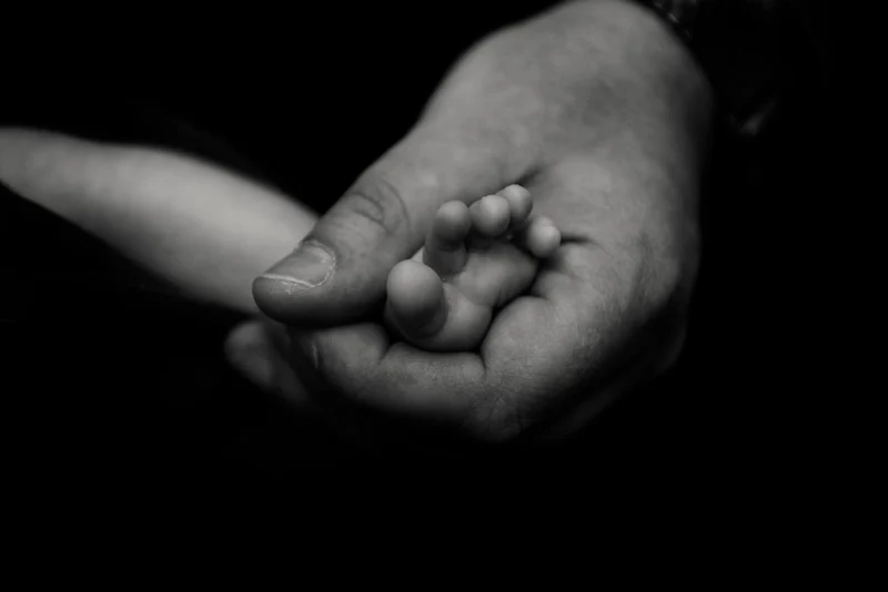 Piccola mano di neonato stretta a un dito, in bianco e nero — Veronica Garavaglia